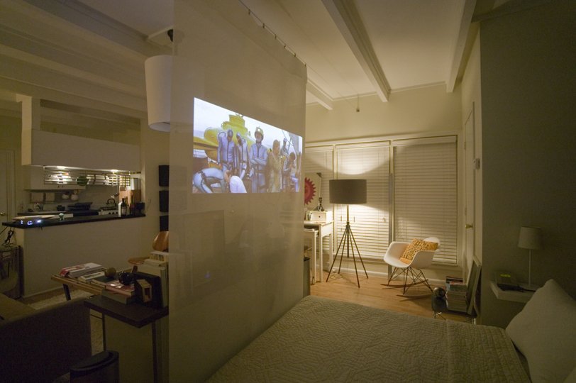 A movie projector screen is an easy way to separate a studio apartment.